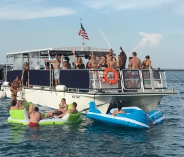 Large party boat rental on Lake Michigan with guests swimming and relaxing on inflatable floats.